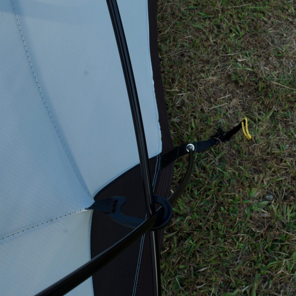 Close-up of a tent pole with a yellow tip on grass