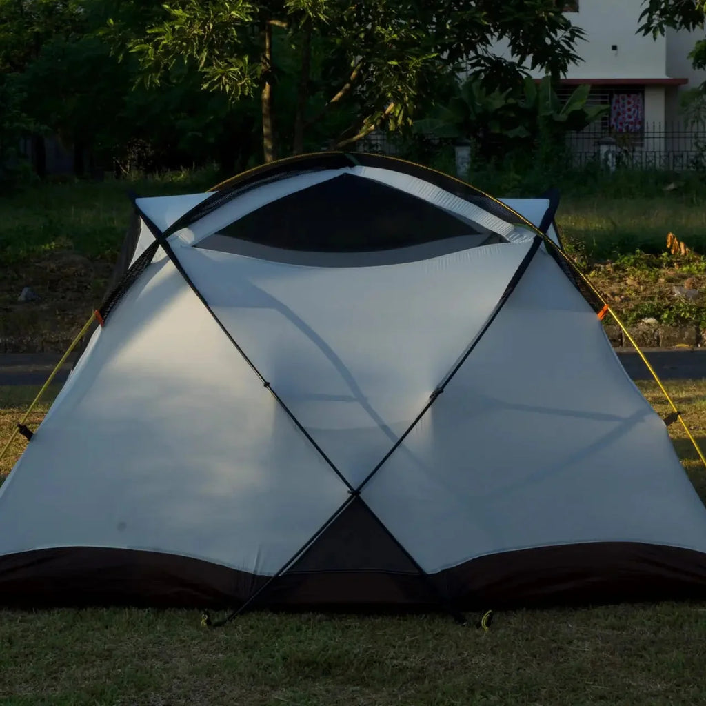 Tent set up on grass with a building and trees in the background